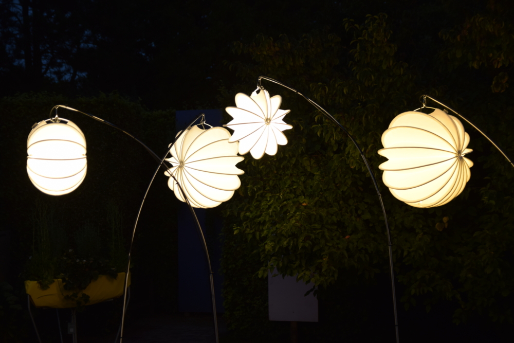 Weiße Barlooon Lampions am Erdspieß mit Lichtinstallation beim Park der Gärten bei Dunkelheit. Weiße Barlooon Lampions am Erdspieß mit Lichtinstallation beim Park der Gärten bei Dunkelheit.